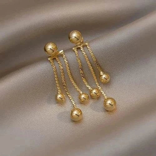Golden Pea Tassel Drop Earrings for women with dangling gold chains and spheres on a silky background