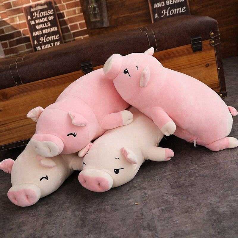 Set of soft doll lying plush piggy toys in pink and white colors on floor