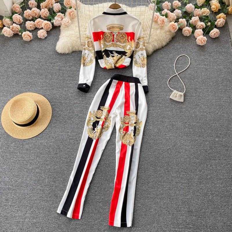 Womens 2 piece set with black, white, and red vertical stripes and ornate gold patterns, styled with a straw hat and small handbag on gray background