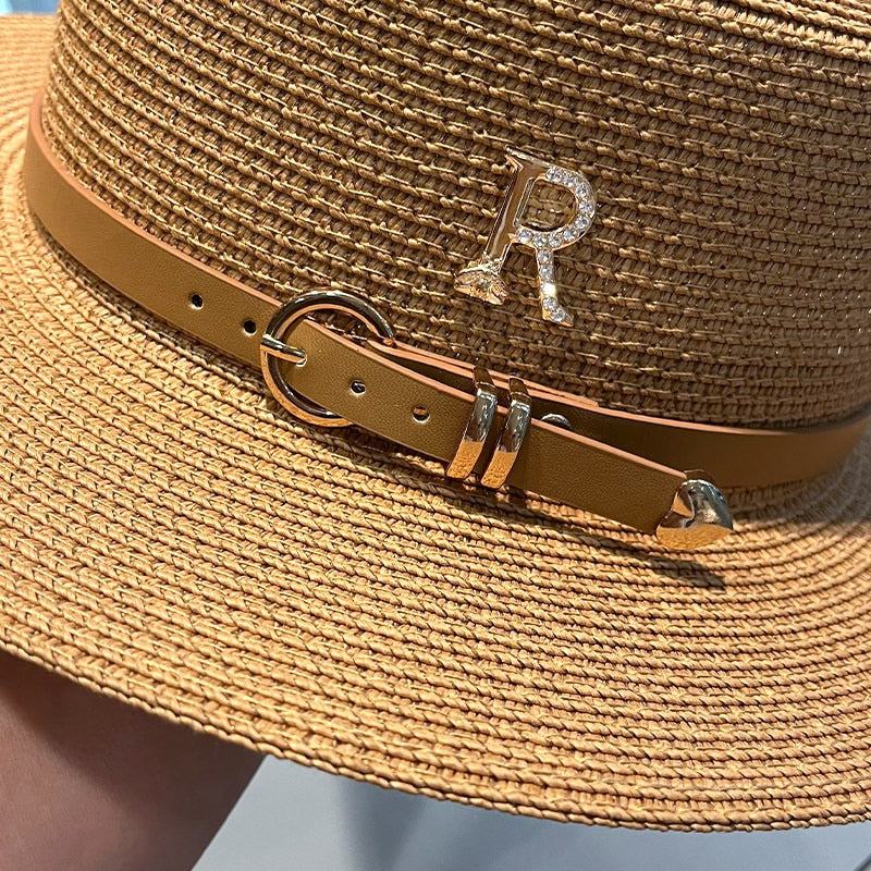 Close-up of women's fashionable beach hat with metal R letter buckle and brown leather strap