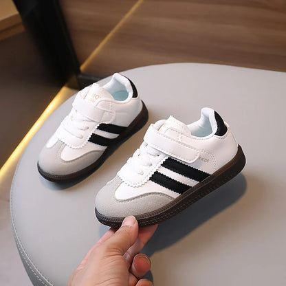 unisex sneakers for kids white with black stripes and velcro strap displayed on table