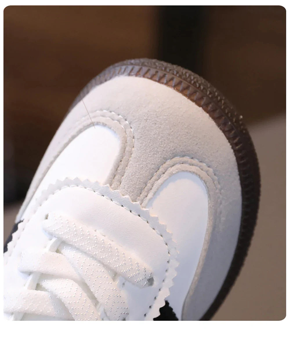 Close-up of white and gray unisex sneakers for kids with laces and textured sole