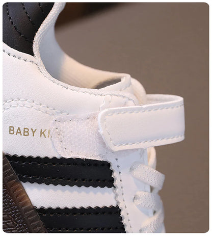 Close-up of white and black unisex sneakers for kids with velcro strap and laces